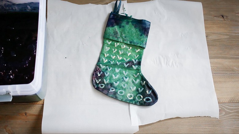 Stocking with indigo dye oxidizing on wax paper next to bucket of dye