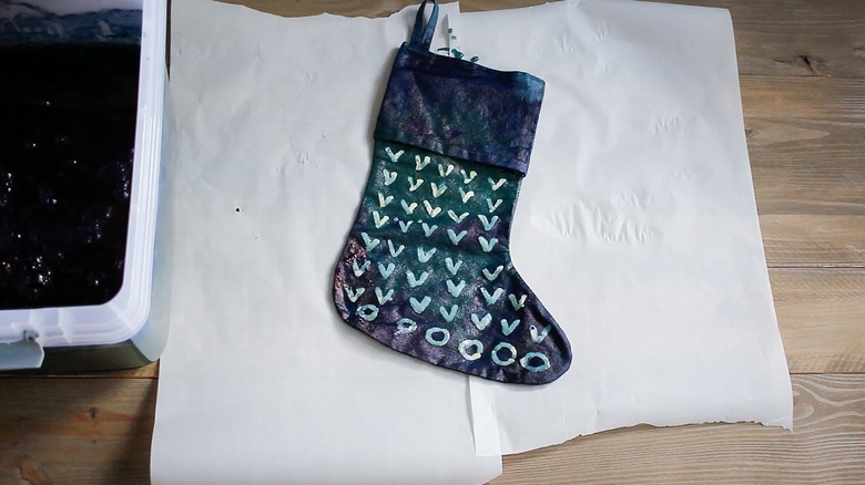 Indigo stocking on wax paper next to bucket of dye