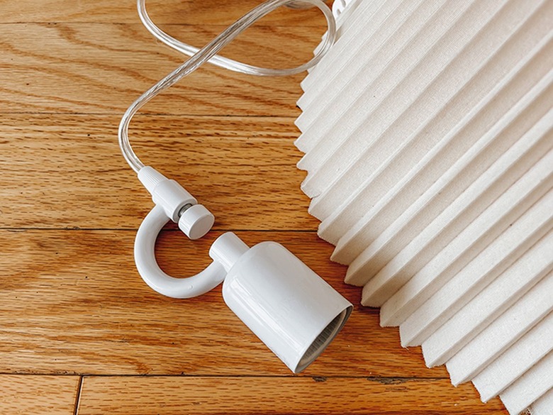 This wired light socket is made to go around the small hole traditionally used for a lamp shade's bolt and finial.