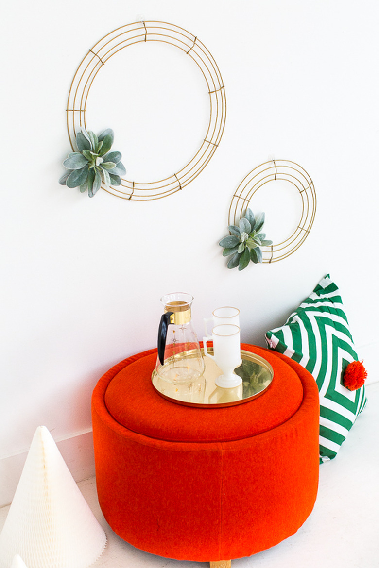 Simple DIY minimalist wreath above red ottoman and green patterned pillow