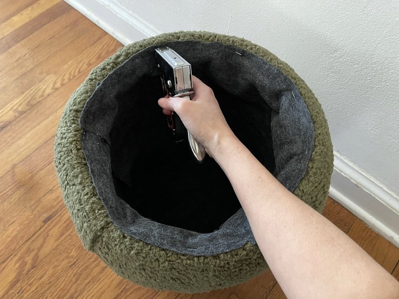 Stapling gray felt fabric inside bucket to create a finished lining