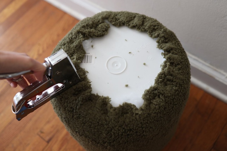 Stapling green sherpa fabric around bucket