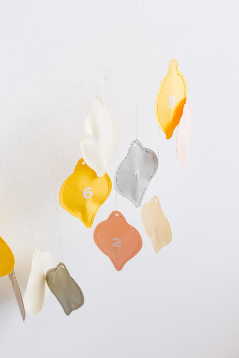 a diy advent calendar with colorful hand-sewn numbered charms shaped like christmas lights