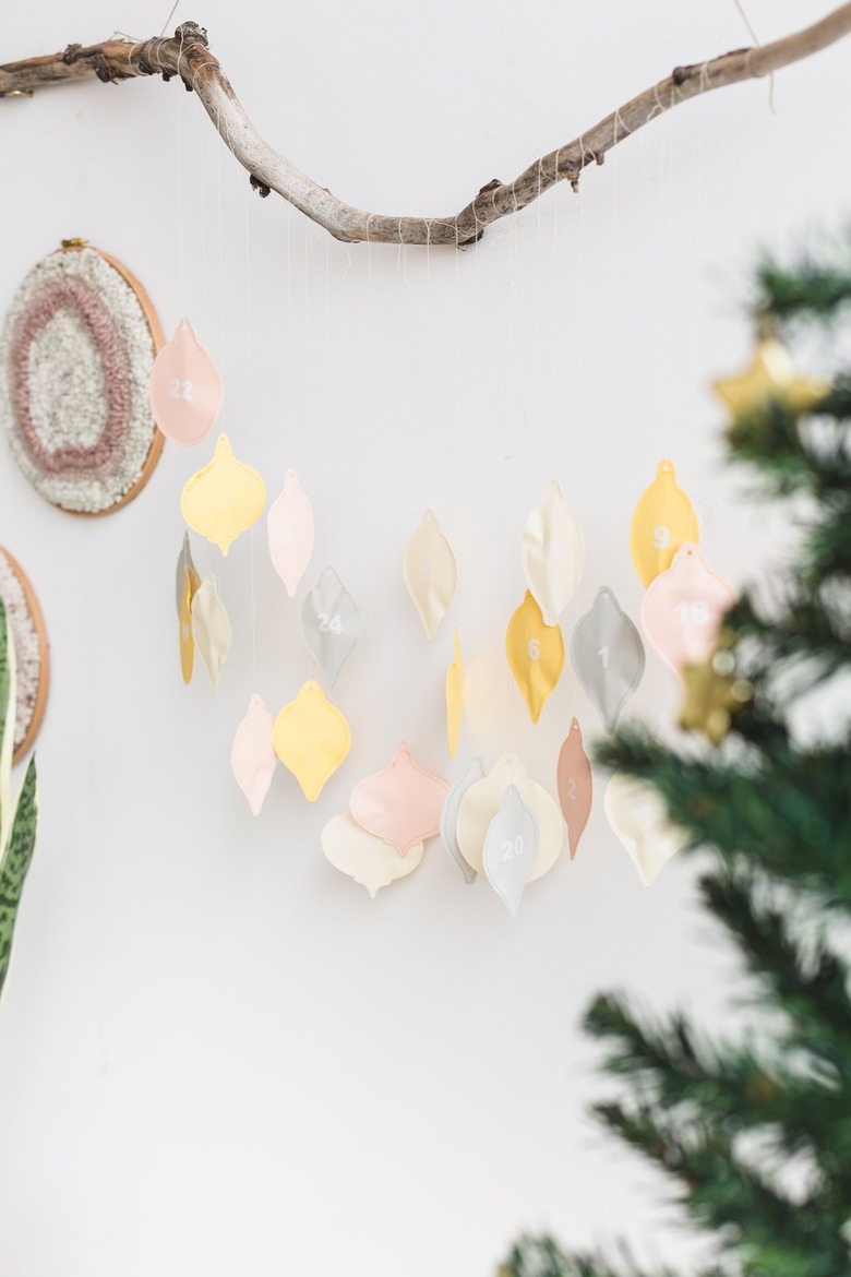 a diy advent calendar with colorful hand-sewn numbered charms shaped like christmas lights