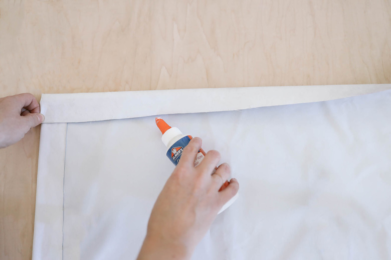 Folding and gluing the raw edges on the top and sides of the blackout fabric