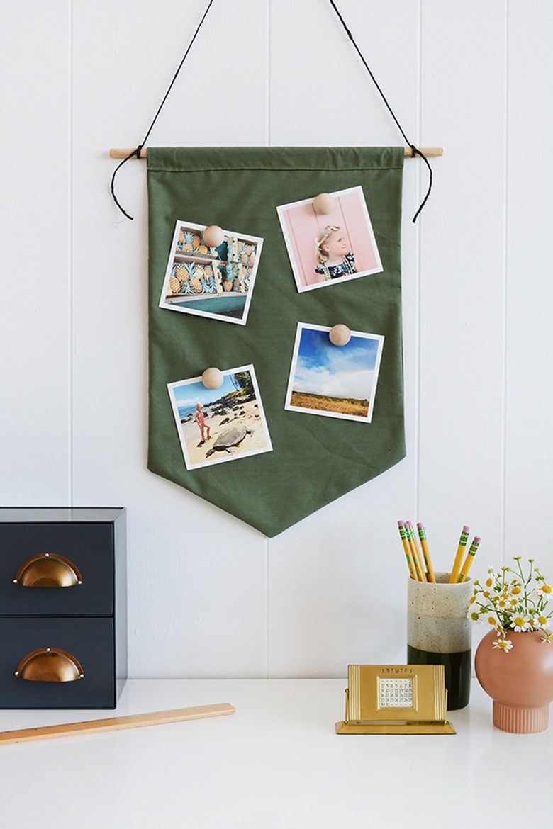 square photos attached to a green pendant with magnets attached to wooden knobs
