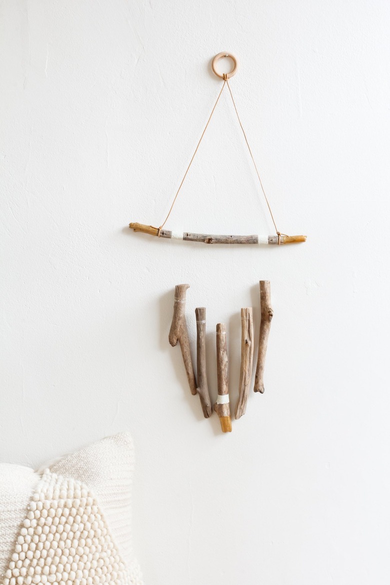 a wall hanging made of several vertical pieces of driftwood suspended from a horizontal one