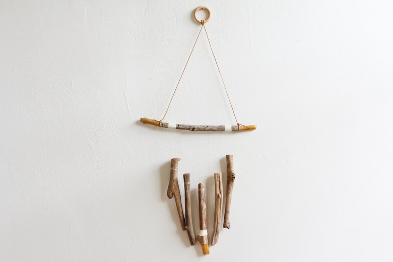 a wall hanging made of several vertical pieces of driftwood suspended from a horizontal one