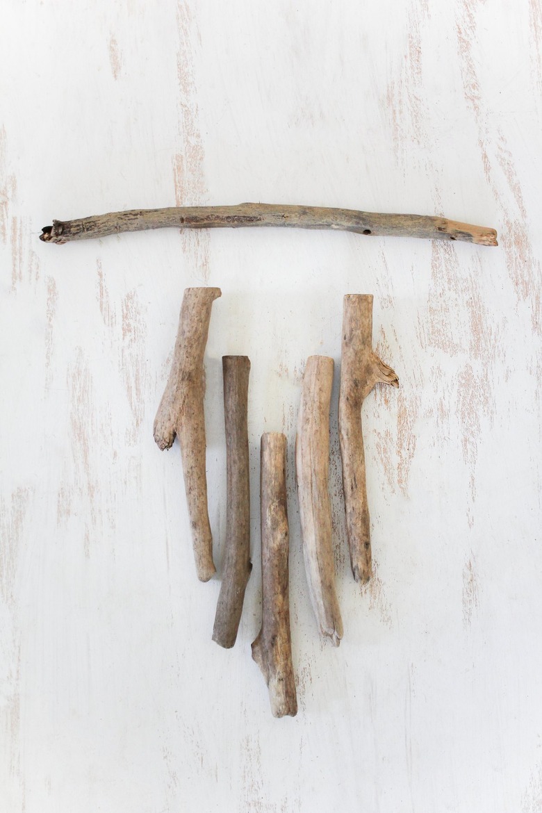 a diy wall hanging project in progress with sticks lined up as they will appear in the final product