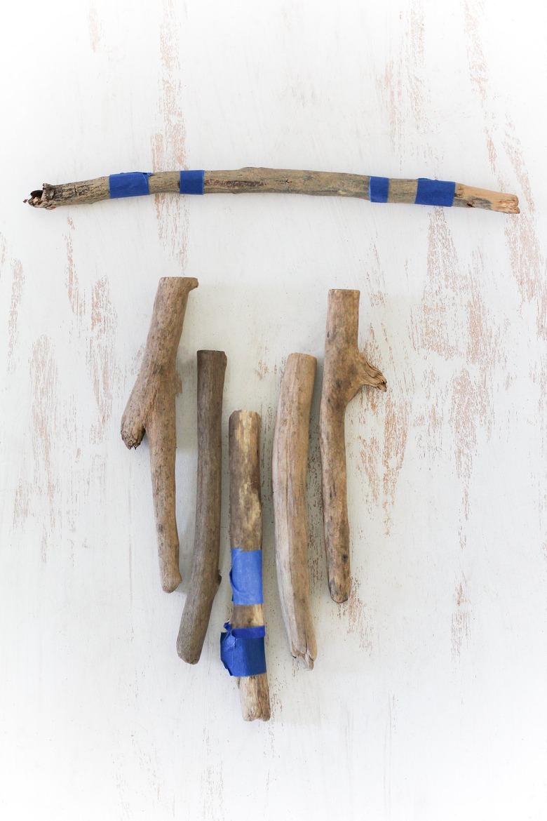 a diy wall hanging project in progress with painter's tape wrapped around several sticks