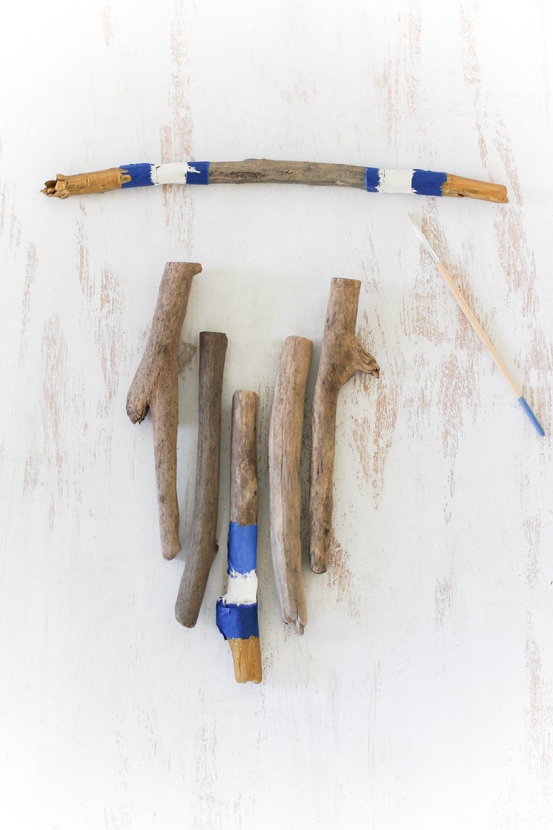 a diy wall hanging project in progress with painter's tape wrapped around several sticks