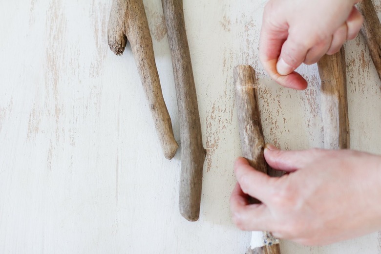 a diy wall hanging project in progress with fishing line wrapped around several sticks