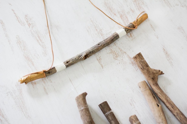 a diy wall hanging project in progress with leather cord attached to the horizontal support