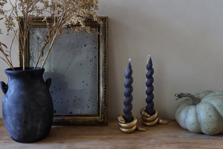DIY gold snake candleholders with black spiral taper candles on table with pumpkin