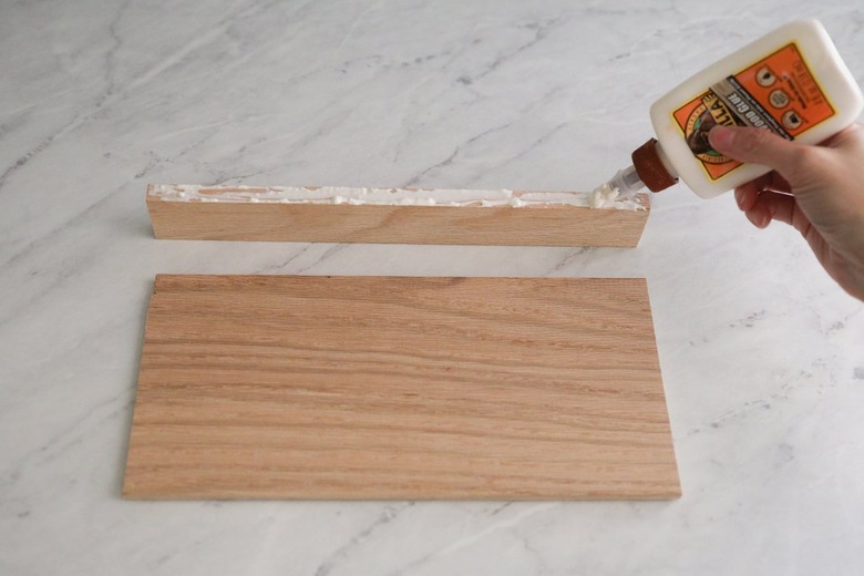 Piping wood glue along one edge of 1-by-2 wood board