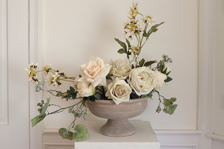 Variety of cream and peach hued roses placed in center of compote bowl