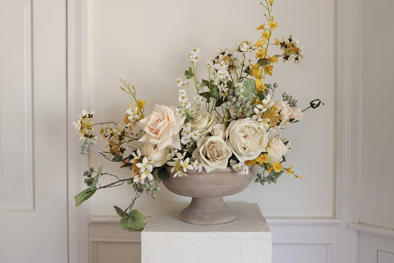 Additional berry branches and viburnum flowers placed inside compote bowl