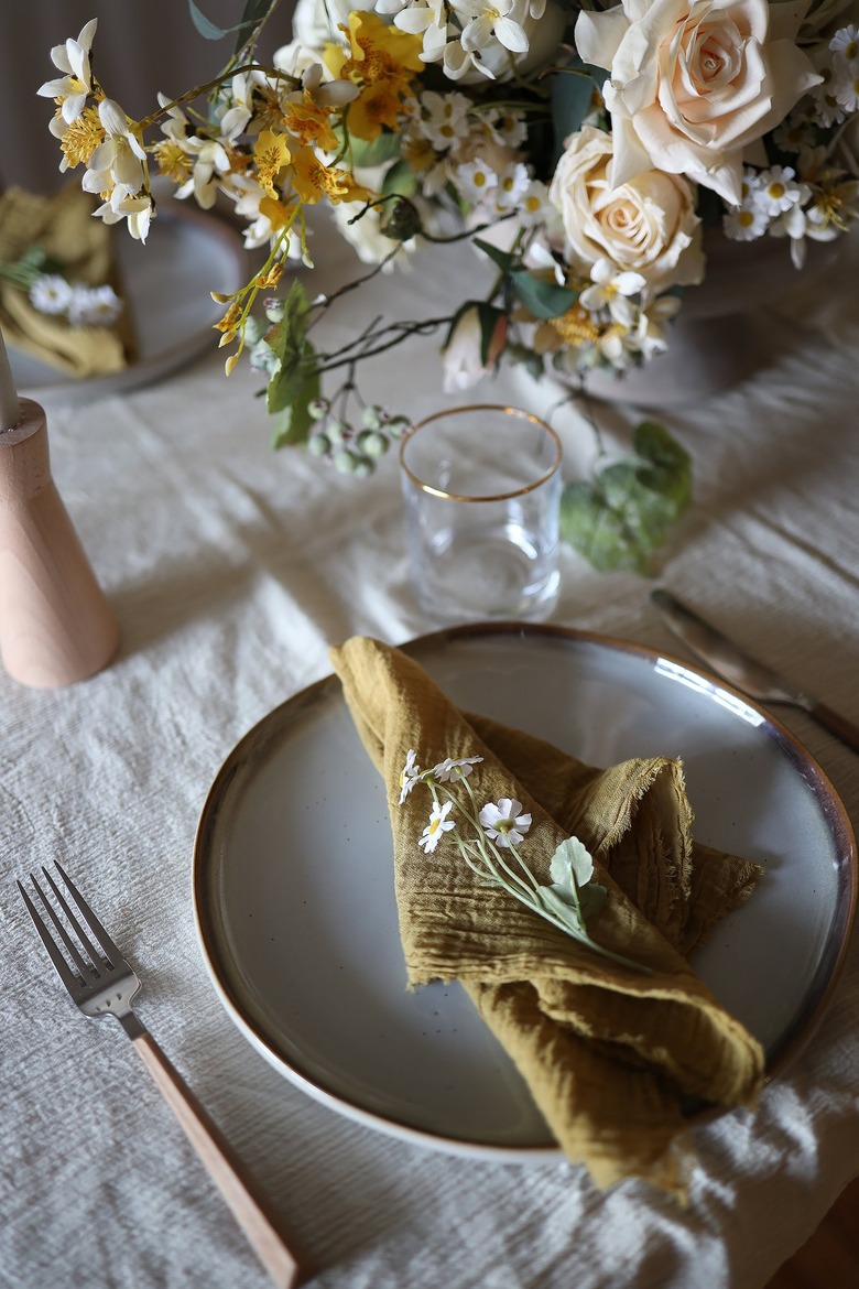 Mini daisy flowers placed on top of golden ochre cloth napkin
