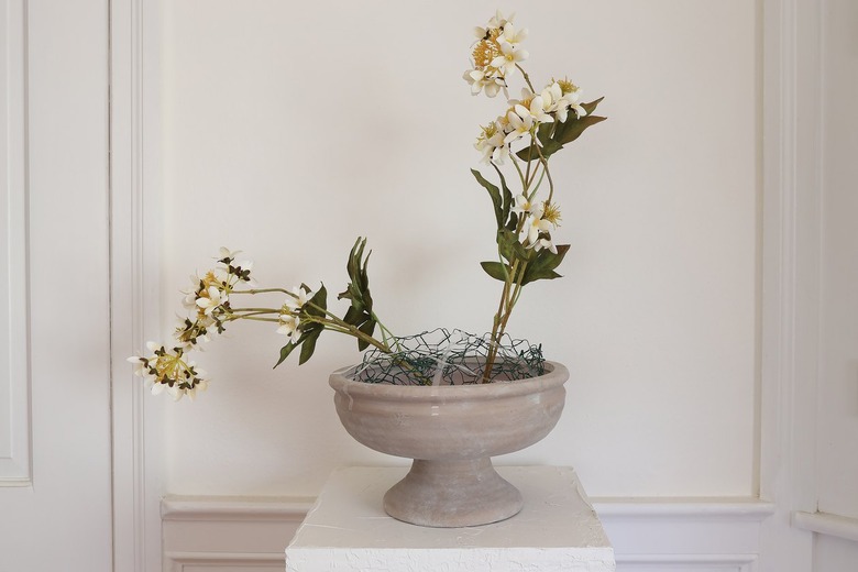 Two stems of cream viburnum flowers placed inside chicken wire