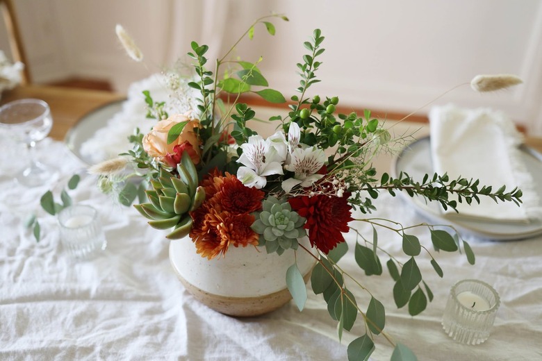 Succulent floral centerpiece on table with candles and place settings