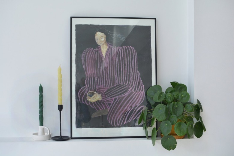 Spiral candles in candlesticks next to artwork