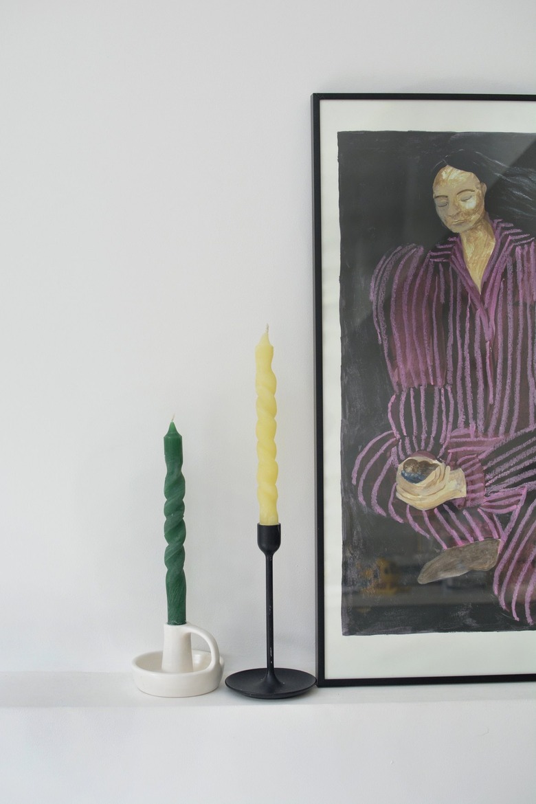 Spiral candles in candleholders next to artwork