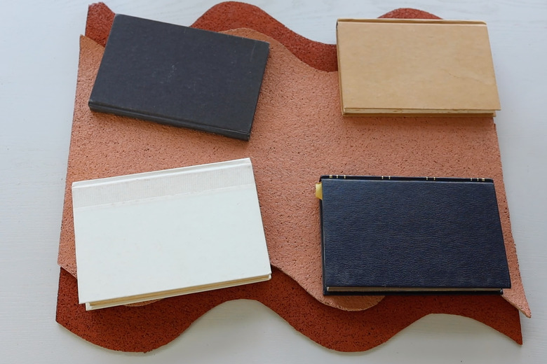 Four books holding two wavy cork pieces flat while glue dries