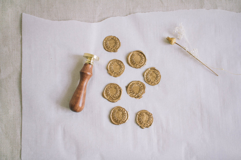 Eight gold wax seals cooling on parchment paper