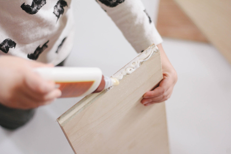Little boy piping wood glue onto wood board