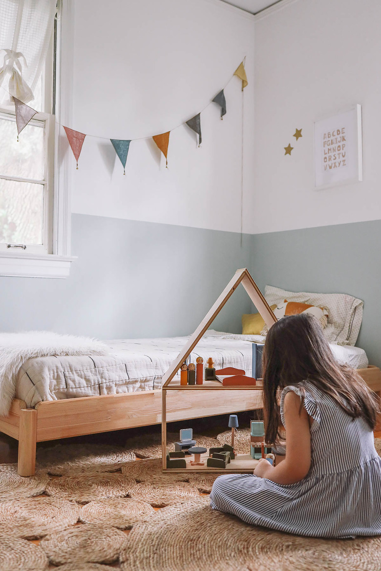 Little girl playing with wooden dollhouse