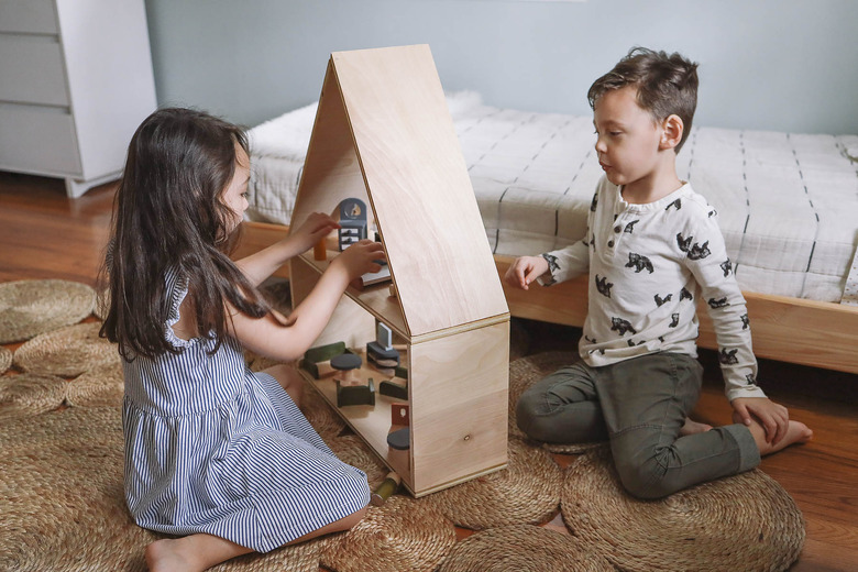 Little girl and boy playing with dollhouse