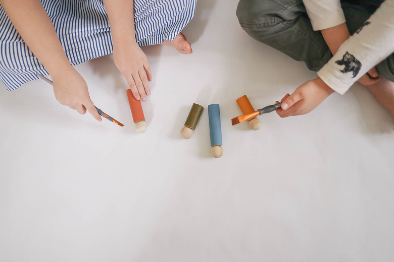 Little girl and boy painting wood dolls