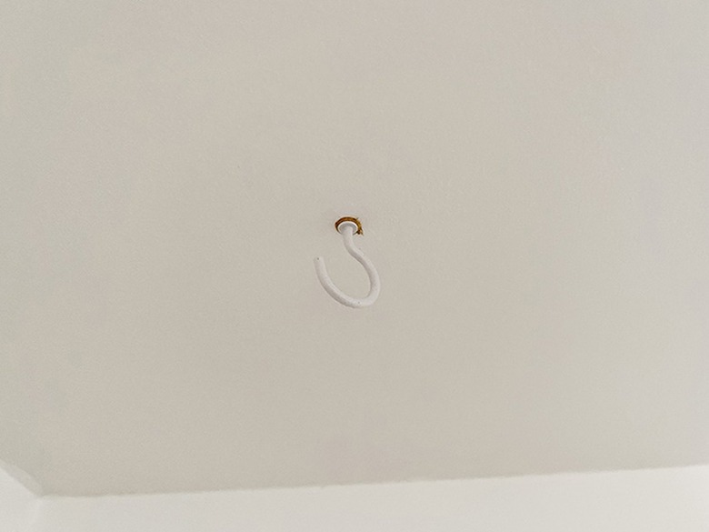 Install a cup hook in the ceiling using a drywall anchor