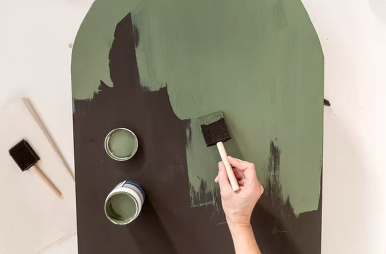 Painting green paint over black wood board