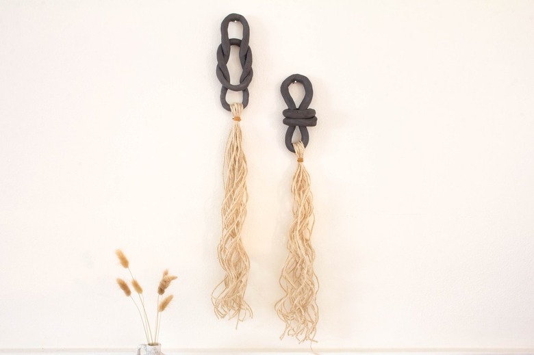 Black air dry clay with ivory jute twine on white wall next to plant