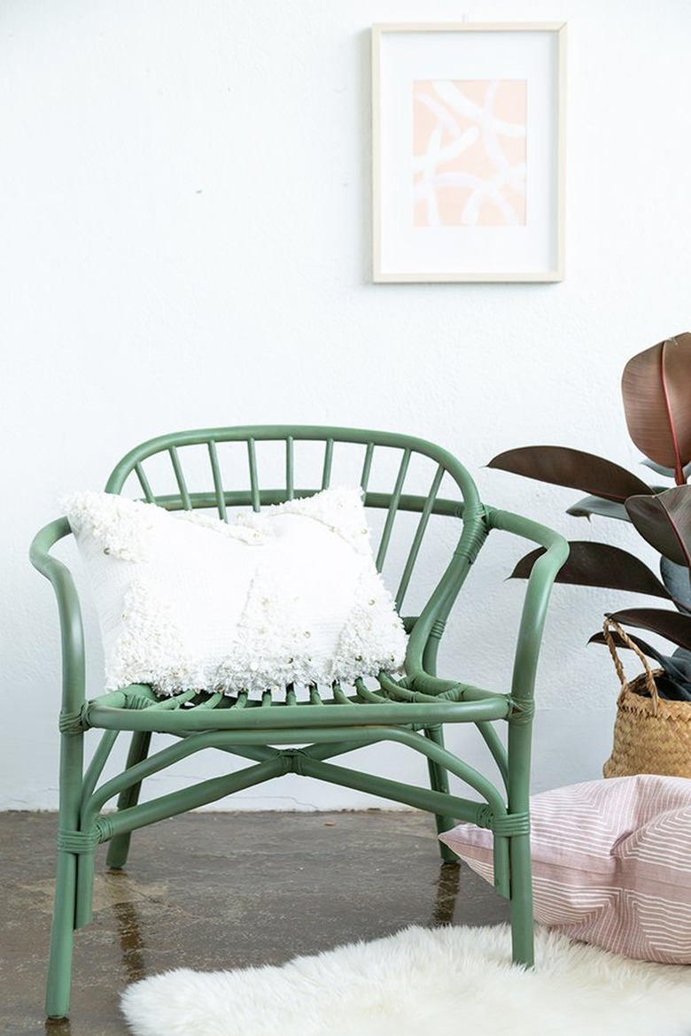 Rattan chair spray painted green with white pillow.