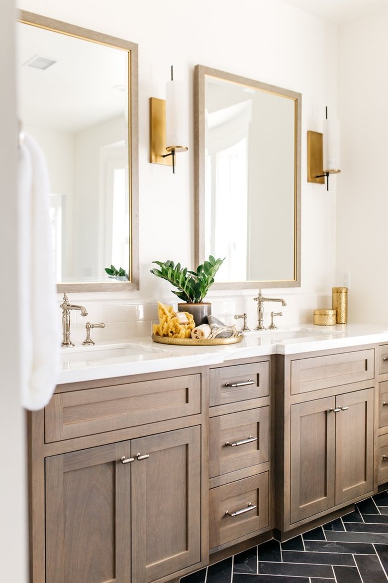 Double bathroom vanity with wood cabinets and wall sconces