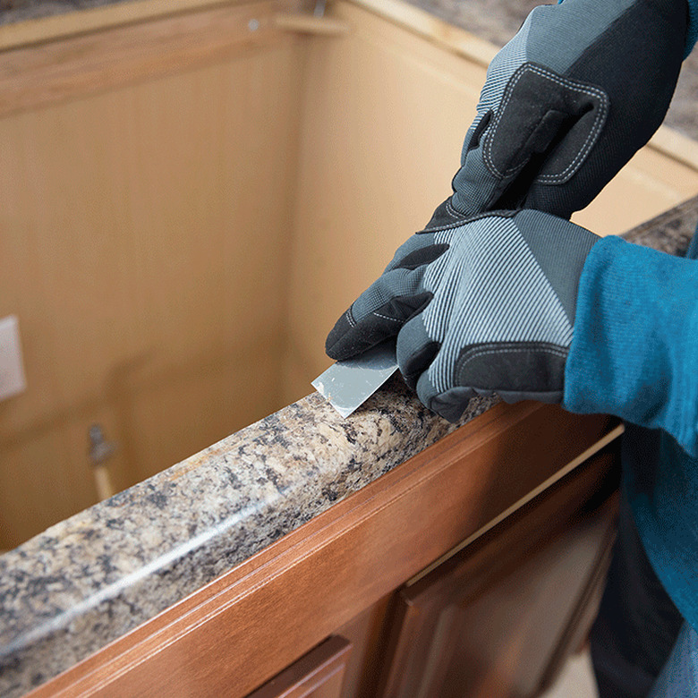 Scraping caulk from countertop.