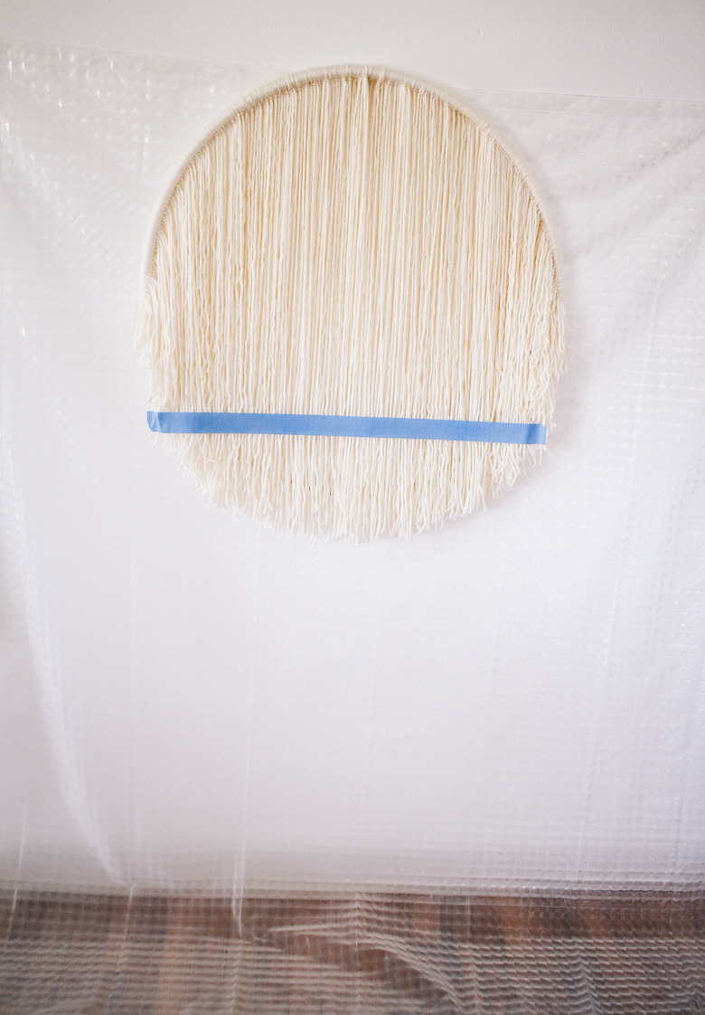 Plastic sheet hung behind hula hoop to protect wall and floor