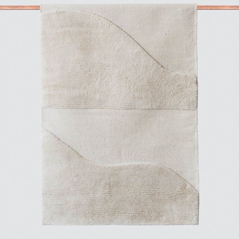 White eco-friendly rug with curved design hanging on copper rod