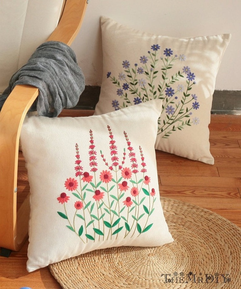 two embroidery pillows on a wood chair