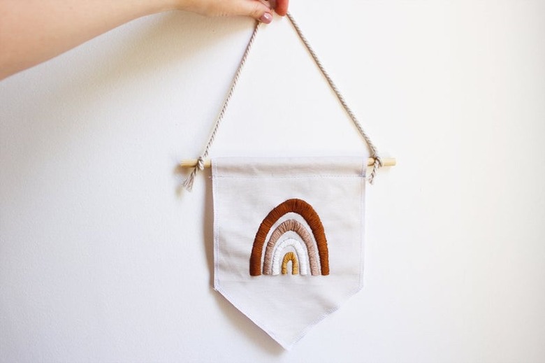 person holding a hanging pennant with rainbow design
