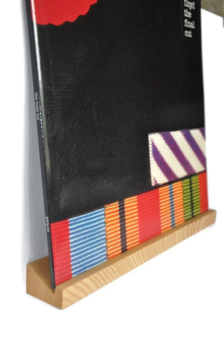 A record perched on a wooden ledge attached to a wall