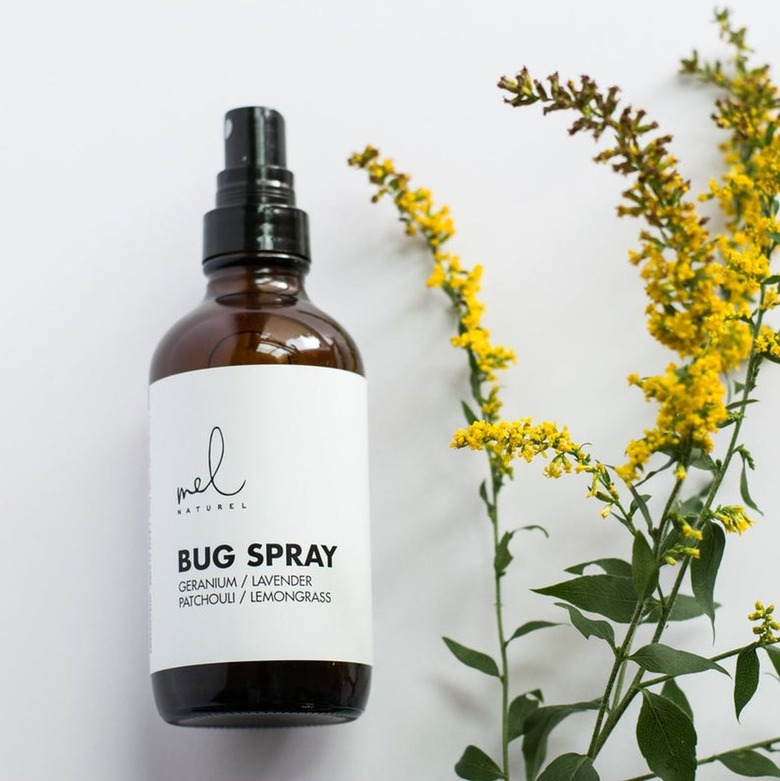 bottle of bug spray next to yellow flower