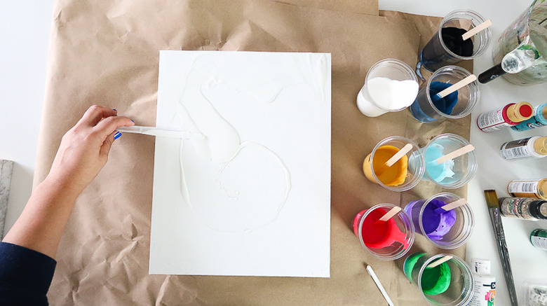 Spreading paint over canvas.