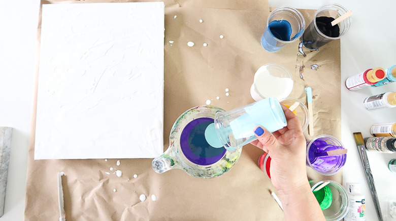 Pouring paint into measuring cup.
