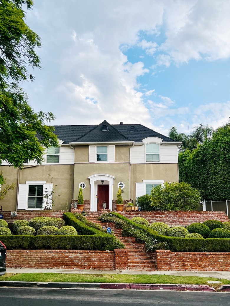 taupe exterior siding with black roof and red brick retaining walls