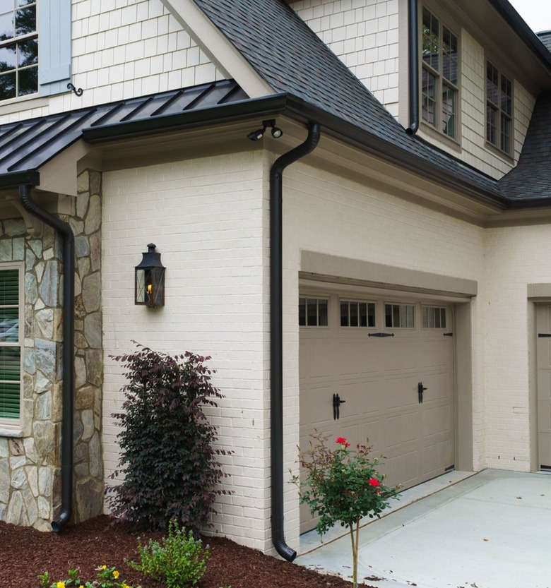 cream siding with black roof and taupe garage door color