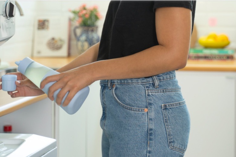 person holding a blue bottle of laundry detergent