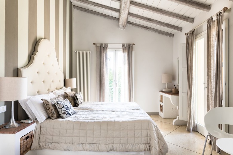 Neutral bedroom with ivory fabric headboard and large windows